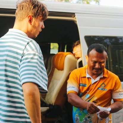 A driver handing a passport back to a client at the minivan